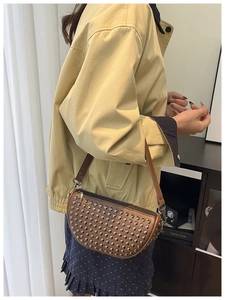 Brown semi-circular shoulder bag with silver rivets shown on model for a stylish look