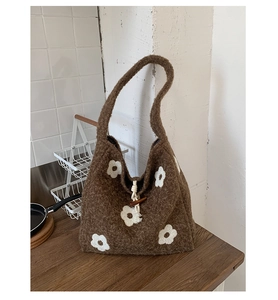 Detailed close-up of brown plush tote bag with white floral embroidery and wooden toggle button