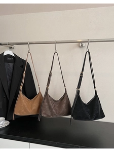 Three vintage hobo shoulder bags in brown and black leather hanging on a rack
