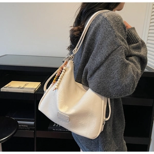 Detail of off-white PU leather tote bag with bohemian beaded charm and metal hardware