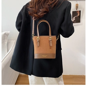 Detailed close-up of brown suede bucket bag featuring high-quality contrast leather and gold hardware