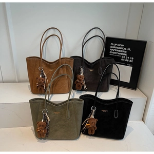 Detailed display of four suede tote bags in brown, green, and black with cute bear charms