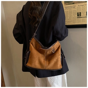 Detail of a large brown suede hobo bag with dark coffee trim and metal ring hardware