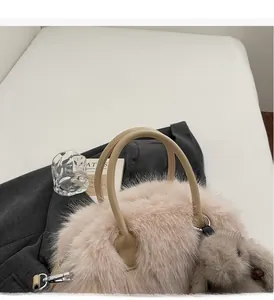 Détail d'un sac cabas en peluche rose avec poignées en cuir et breloque lapin sur un blazer