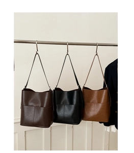 Trois sacs seau minimalistes en noir, marron foncé et caramel sur présentoir