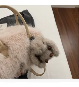 Détail du sac à main en peluche rose avec un charm lapin gris et des poignées lisses