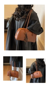 Detail of caramel brown lychee leather pillow bag with gold lettering and woven charms
