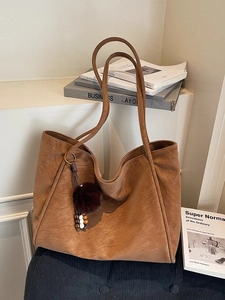 Borsa tote minimalista in pelle marrone con ciondolo decorativo e stile vintage chic