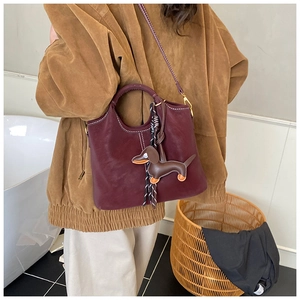 Detail der burgunderroten Bucket Bag aus Leder mit Kontrastnähten und Hundeanhänger