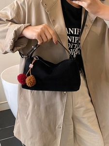 Sac oreiller en daim noir avec breloque cerise en peluche sur un trench-coat