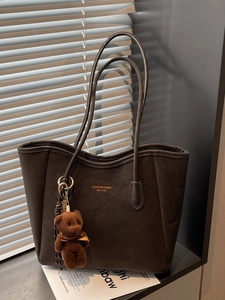 Vintage brown leather tote bag with brand logo and cute plush bear charm decoration