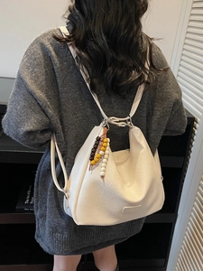Retro cream faux leather shoulder bag with decorative wooden beads on a casual model