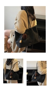 Detail of black suede tote bag featuring a decorative fur ball and wooden bead charm