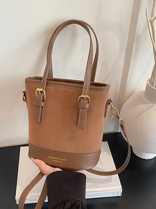 Retro brown bucket bag with suede texture and dual handles shown in a lifestyle setting