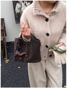 Detail der grauen Nubuk-Eimertasche mit weißen Nähten und Dackel-Lederanhänger im Herbst