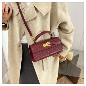 Dettaglio della borsa a tracolla in pelle intrecciata bordeaux con chiusura girevole dorata