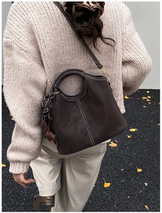 Detail der dunkelbraunen Eimer-Tasche aus Wildlederimitat mit Kontrastnaht und Anhänger