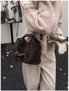 Detail einer dunkelbraunen Leder-Eimertasche mit weißen Kontrastnähten und Hundeanhänger