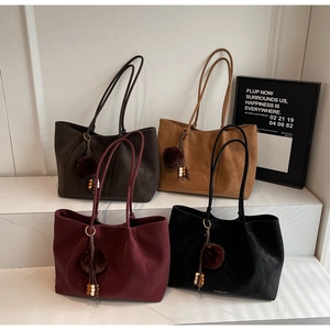 Detailed view of large suede tote bags in four colors with decorative tassel charms