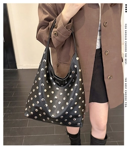 Détails de clous argentés sur un sac hobo noir en cuir porté par un mannequin de mode