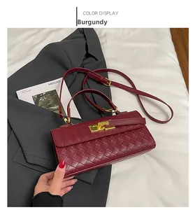 Dettaglio borsa a mano intrecciata bordeaux con chiusura dorata su abito grigio