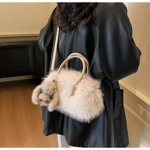 Sac fourre-tout en fausse fourrure beige avec charm lapin porté sur manteau noir