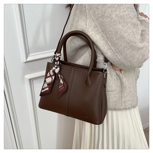 Close-up of brown litchi pattern leather tote with a decorative silk scarf on the handle