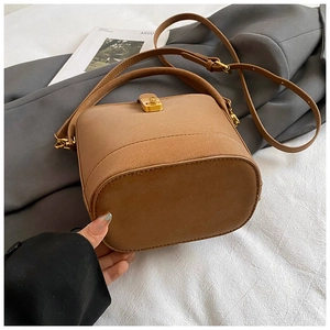 Detail of retro brown bucket bag featuring gold twist-lock and fine leather texture