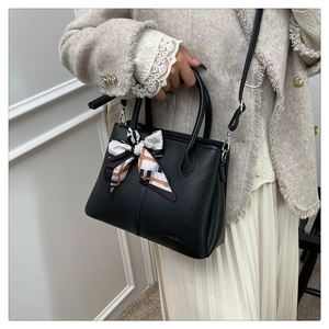 Detail of black lychee grain leather bucket bag with decorative printed silk scarf handle