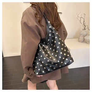 Détails des rivets argentés sur le sac hobo noir au style punk rétro et industriel