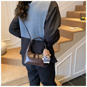 Détail d'un sac hobo marron vintage en cuir brillant avec un charmant pendentif chiot peluche