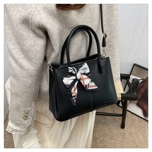 Detail of black pebbled leather bucket bag with elegant chain-pattern silk scarf handle