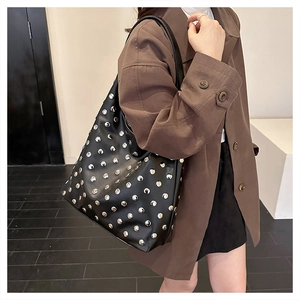Gros plan de clous argentés sur sac hobo en cuir noir au style punk et vintage