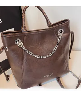 Dettaglio della borsa tote in pelle marrone scuro con catena e fibbia floreale