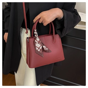 Deep red pebbled leather bucket bag with decorative silk scarf and embossed logo detail