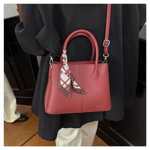 Detailed shot of red lychee pattern bucket bag with silk scarf and embossed logo