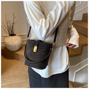 Detail of dark brown nubuck bucket bag featuring golden clasp and dual strap options