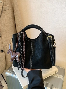 Minimalistische schwarze Eimertasche mit weißen Kontrastnähten und Pferdeanhänger auf Koffer