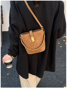 Detail of vintage brown suede bucket bag with gold clasp and adjustable strap in autumn setting