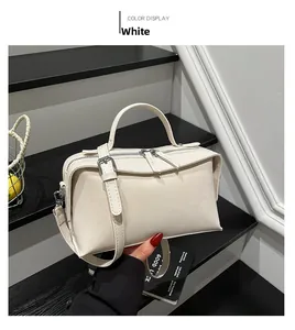 Detail of white faux leather tote bag showing top handle and silver zipper hardware