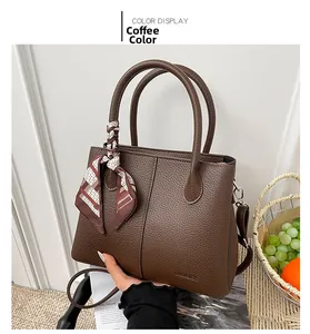 Detail of coffee brown lychee pattern leather bucket bag with a decorative floral silk scarf