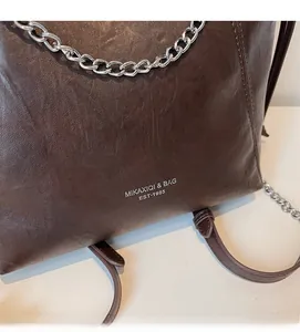 Dettaglio della borsa tote marrone scuro con trama litchi e catena d'argento