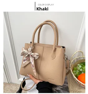 Macro view of khaki lychee leather bucket bag with a silk scarf tied on the handle
