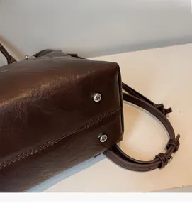 Dettaglio della base della borsa in pelle marrone con piedini protettivi in metallo