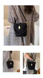 Three-way view of a black leather bucket bag with a gold buckle and adjustable straps