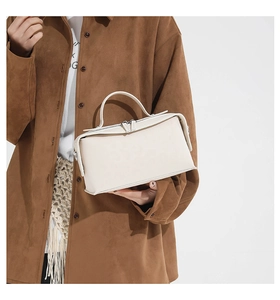 Close-up of cream white leather handbag with silver dual zipper and top handle detail