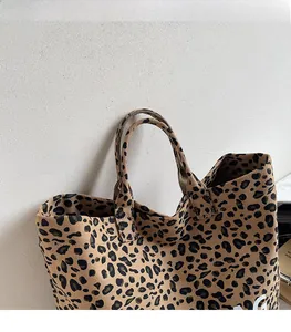 Detail of leopard print tote bag featuring sturdy canvas handles and white letter print