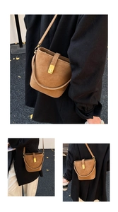 Detail view of a vintage brown bucket bag with a golden turn-lock clasp and shoulder strap