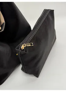 Close-up of black tote bag with matching small zippered inner pouch and gold zipper detail