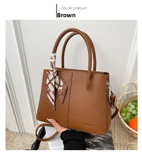 Detail of a brown bucket bag in lychee texture leather with a geometric print silk scarf
